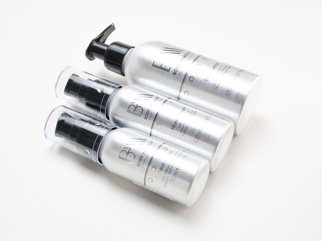 Mens skincare packaging graphic identity shown on three aluminium bottles with black pumps on a white background